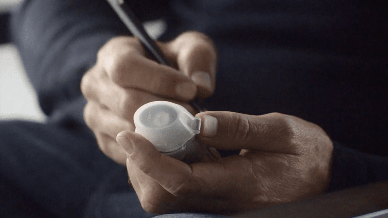 Hands holding an inhaler and a pen.