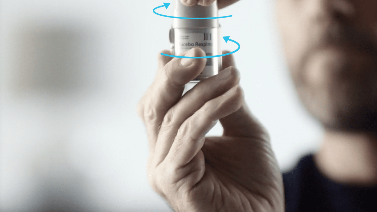 person holding a Respimat inhaler with arrows indicating how to open the cap.