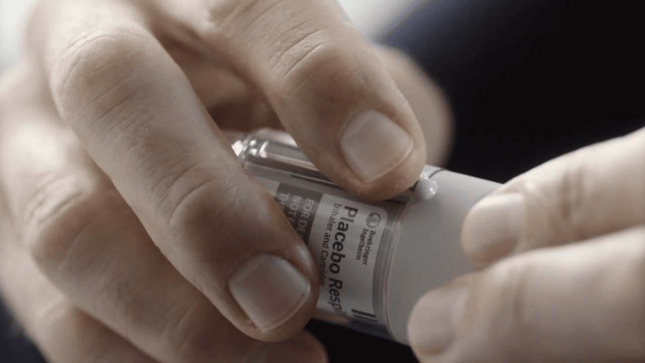 Hands opening a Respimat inhaler device.