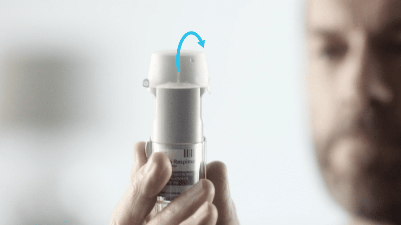 Person turning the clear base of a Respimat inhaler with the cap closed