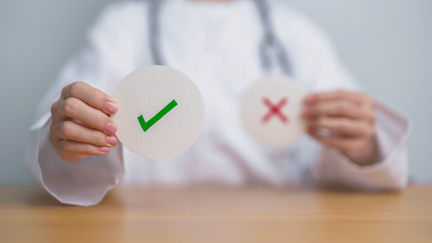 Healthcare professional holding a green checkmark and a blurred red cross sign.