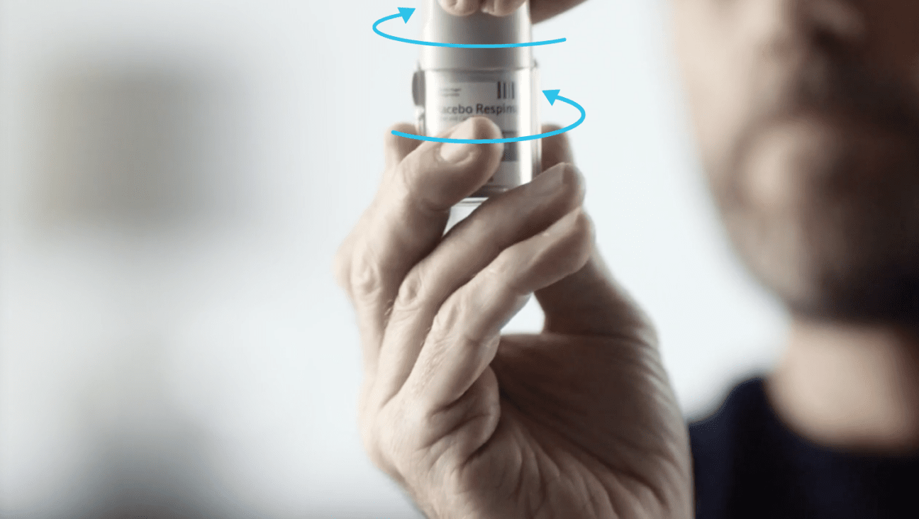 person holding a Respimat inhaler with arrows indicating how to open the cap.