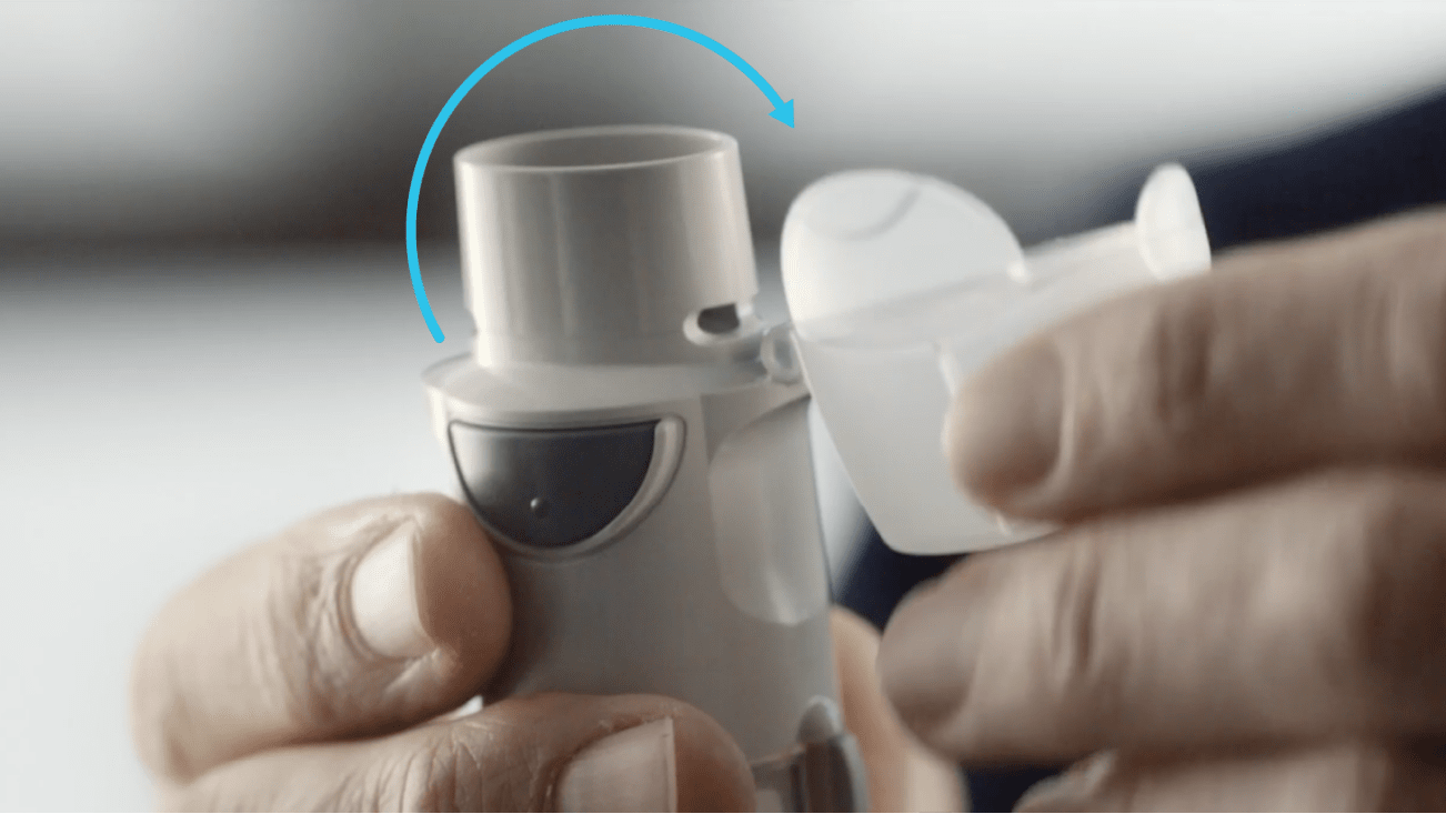 Hands opening the hinged cap of a Respimat inhaler